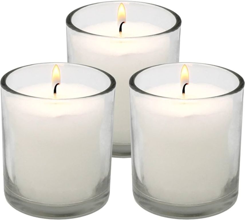 a close up photo of white unscented votive candles burning in glass votive holders.