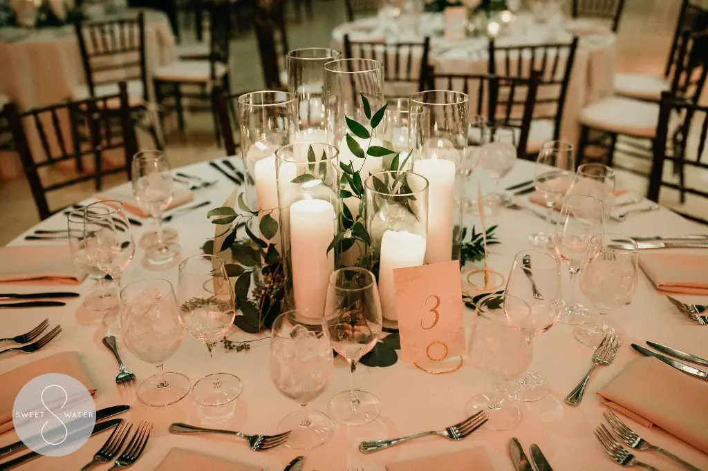 a photo of a variety of pillar candles on a table with a white tablecloth.