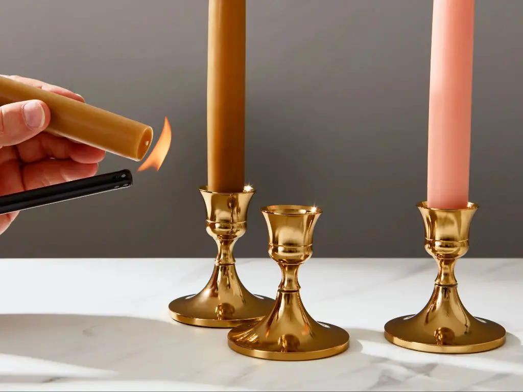 a photo of elegant gold taper candle holders with tall white taper candles.