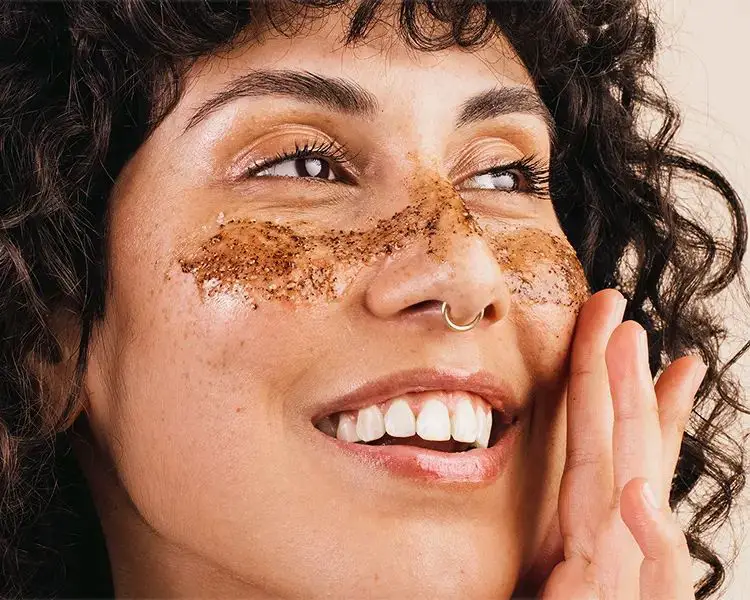 a woman exfoliating her upper lip area with a scrub