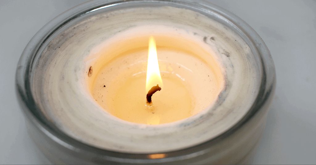 melted candle wax pooling at the base of a burning candle