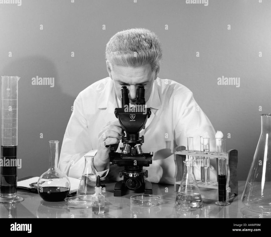 person in a lab coat using a microscope.