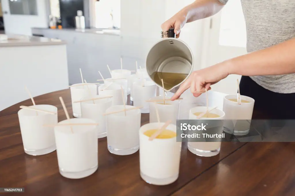 person pouring wax into candle jars.