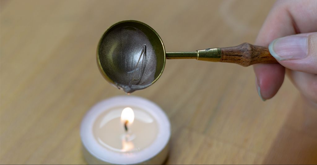 scraping excess candle wax with a spoon