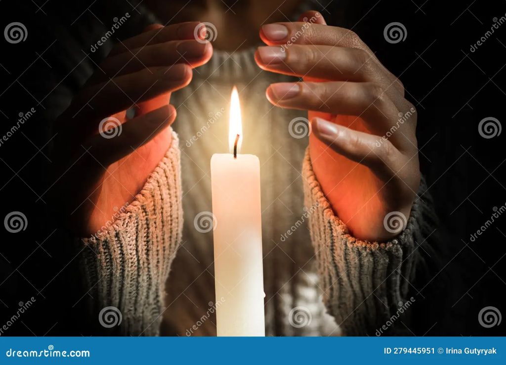 woman warming hands over a candle