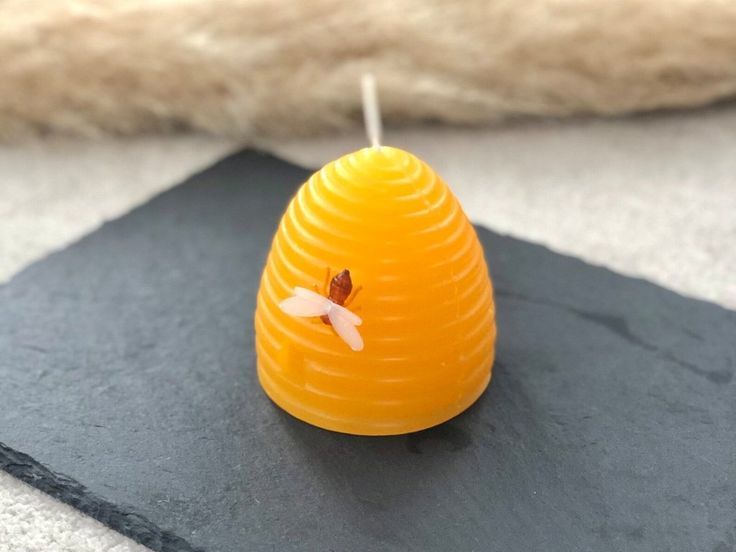 a bee sitting on top of a beeswax candle