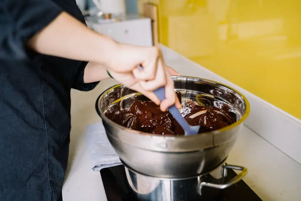 a double boiler heating chocolate, with water simmering in the bottom pot.