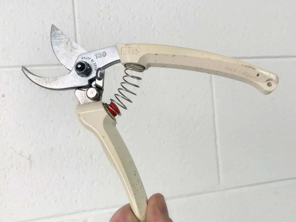 a florist using a stem cutter tool to cut flower stems at an angle.