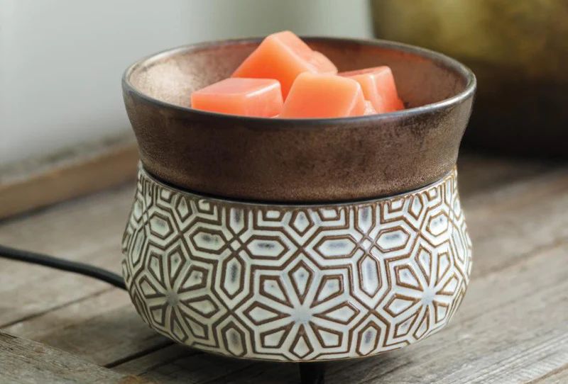 a person adding a cube of wax to an electric wax melter.