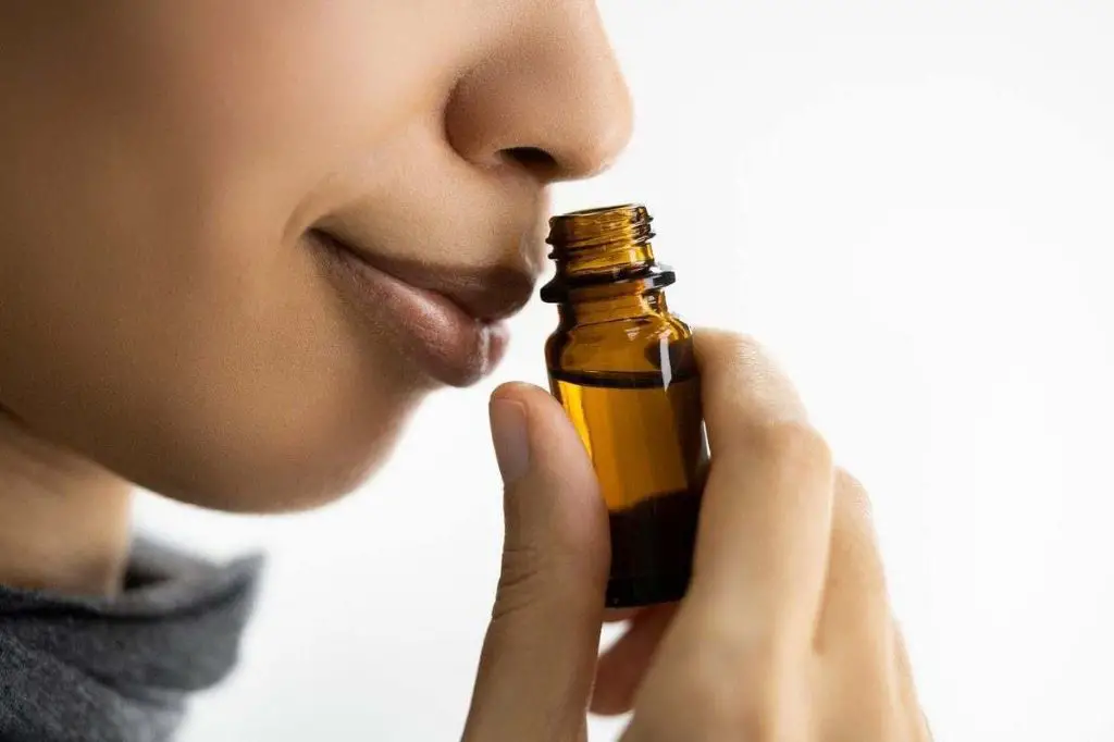 a person carefully mixing small amounts of essential oils in bottles.