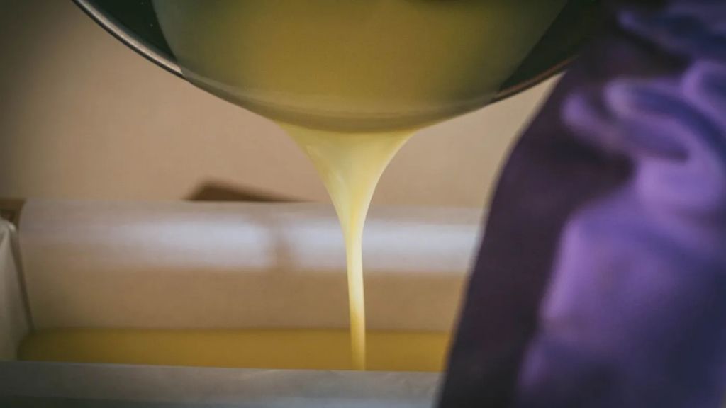 a person carefully pouring soap mixture into silicone molds