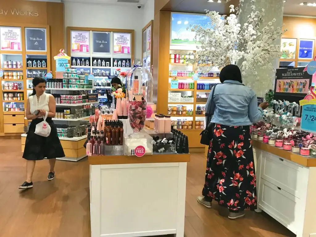 a person in a bath & body works store smelling candles on display.