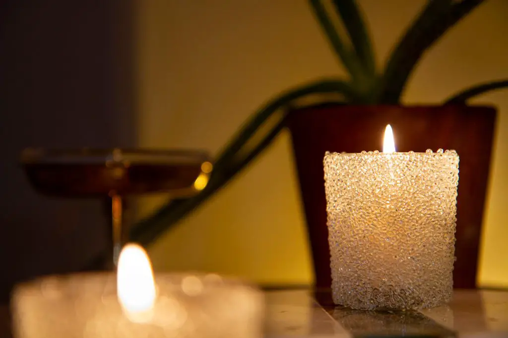 a person placing a candle in a safe glass holder on a heat-resistant surface