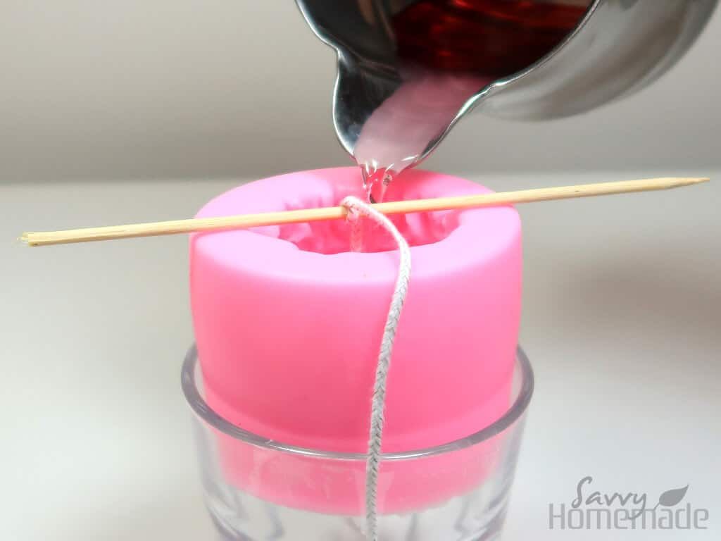 a person pouring wax into a candle mold