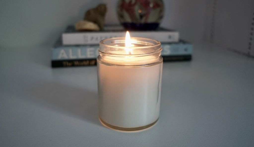 a person selecting a non-toxic beeswax candle over a paraffin candle