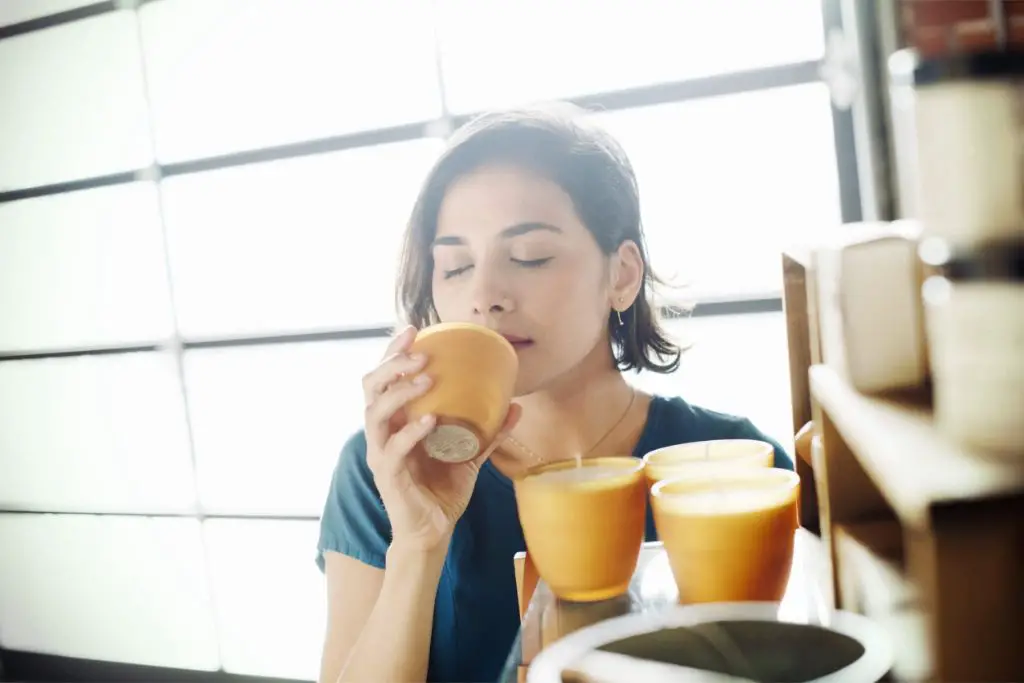 a person smelling a soy candle