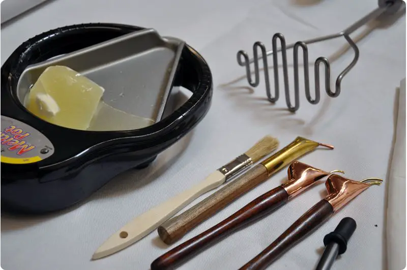 a person using batik wax dyeing tools and materials.