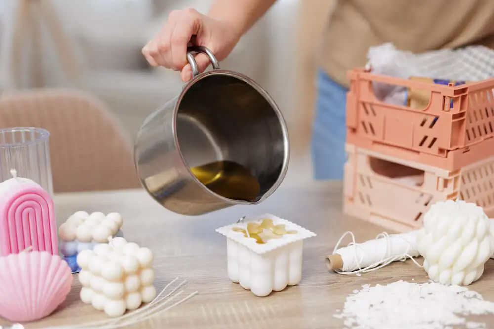 a person wearing protective gloves while pouring hot wax into a silicone mold