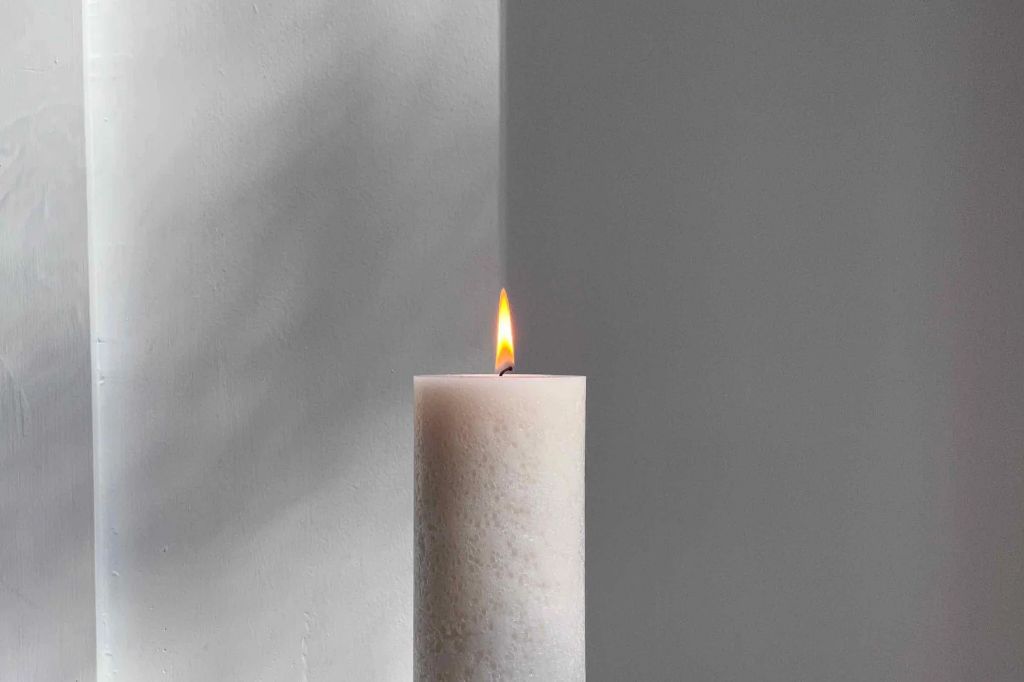 a soy candle burning in a holder and producing a small amount of black soot around the wick