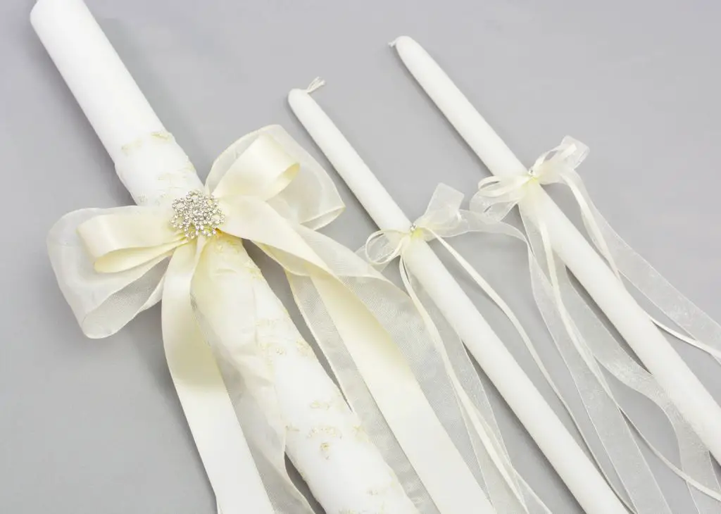 a white pillar candle wrapped in lace and a ribbon bow makes an elegant wedding favor.