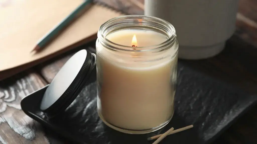 a white votive candle burning inside a short glass container.