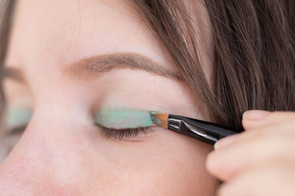 a woman using a makeup brush to apply shimmery eyeshadow containing mica powder