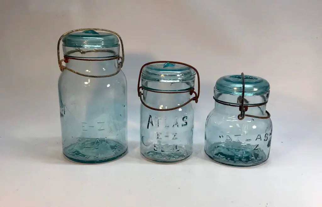 an antique blue bail-top mason jar with embossed lettering on the glass surface.