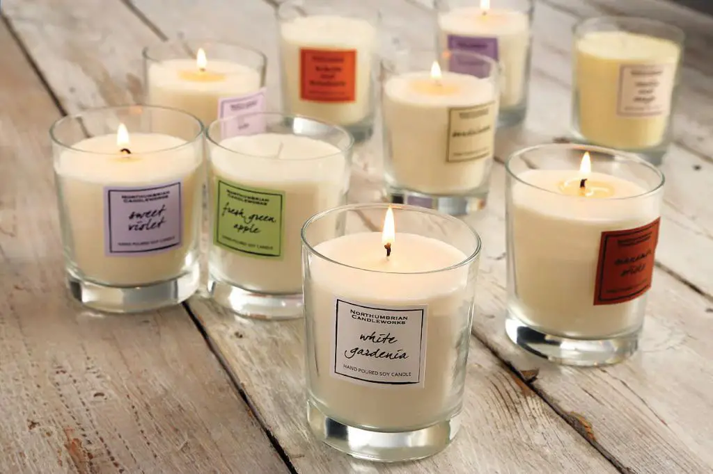 an assortment of colorful scented candles burning inside glass jars.