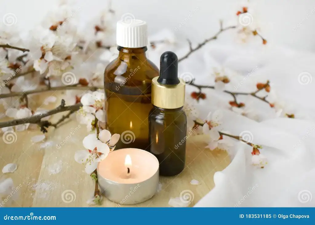 an assortment of essential oil bottles next to a burning candle.