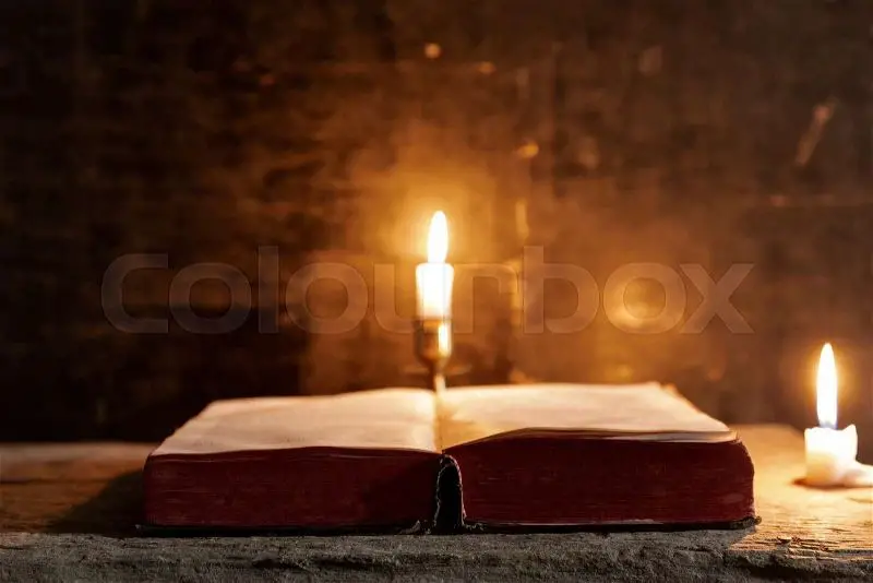 beeswax candle lit next to an open bible, representing the light and sweetness of christ