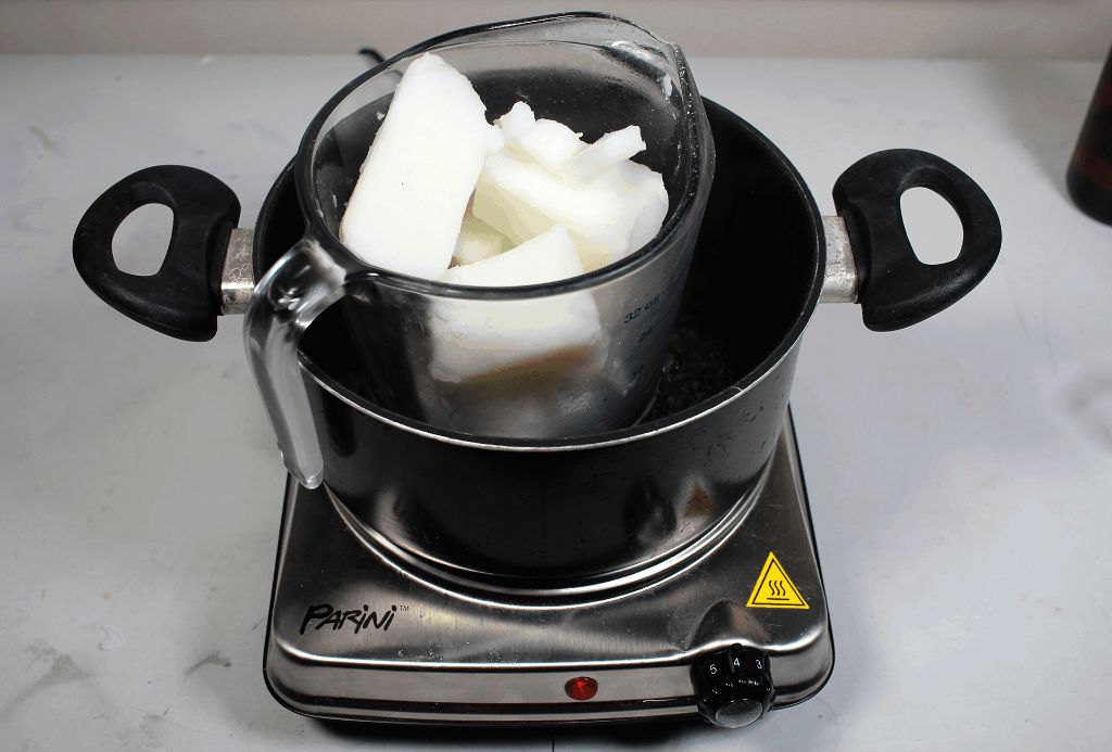 candle wax melting in a mug over a stove