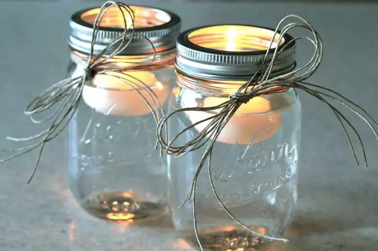 candles presented in glass jars tied with ribbon