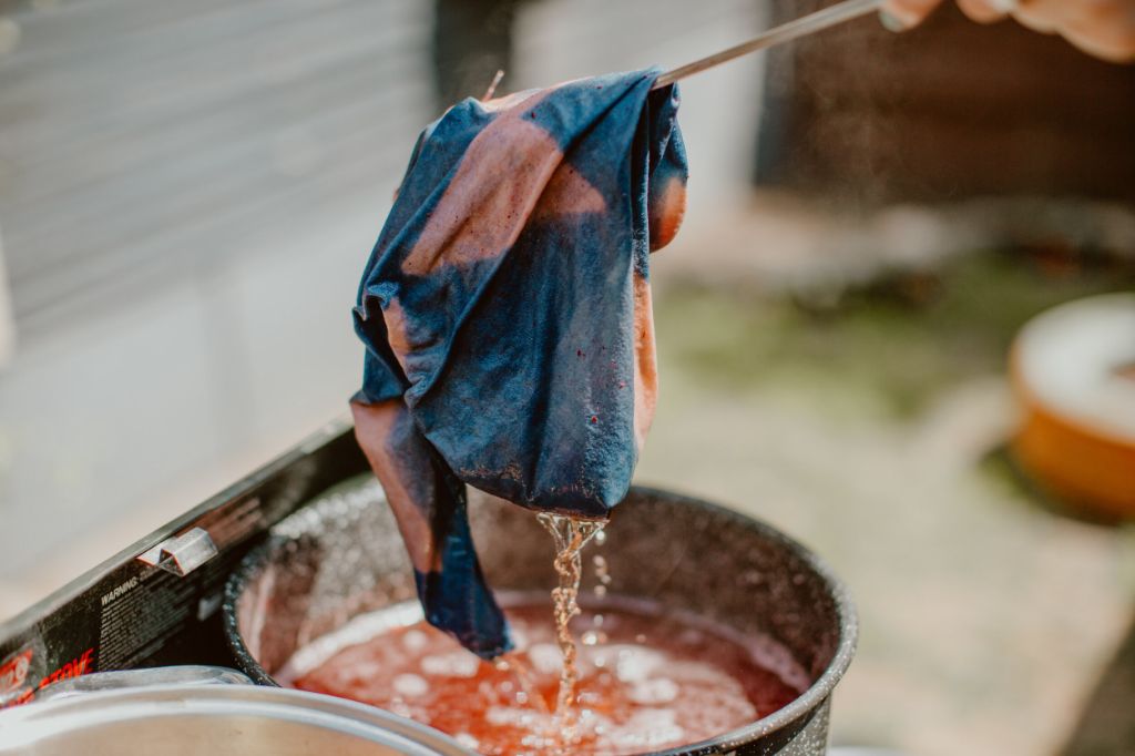 dye powders being mixed into a tub of water to prepare green dye bath.