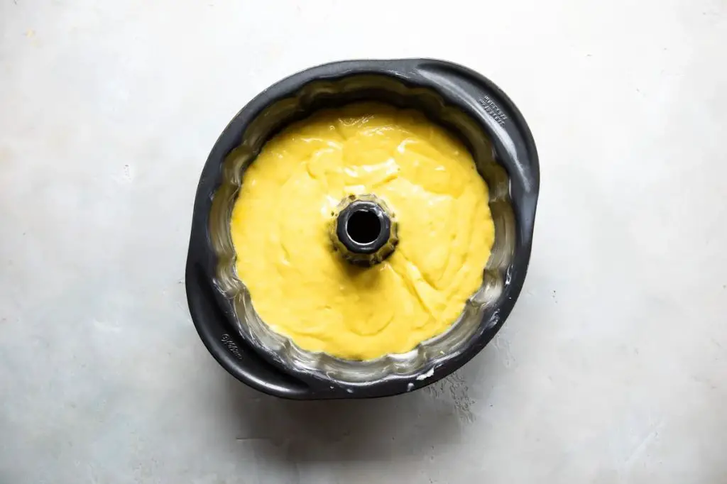 lemon pound cake batter being poured into a bundt cake pan