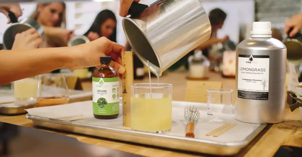 man adding fragrance oils to melted paraffin wax while preparing scented candles