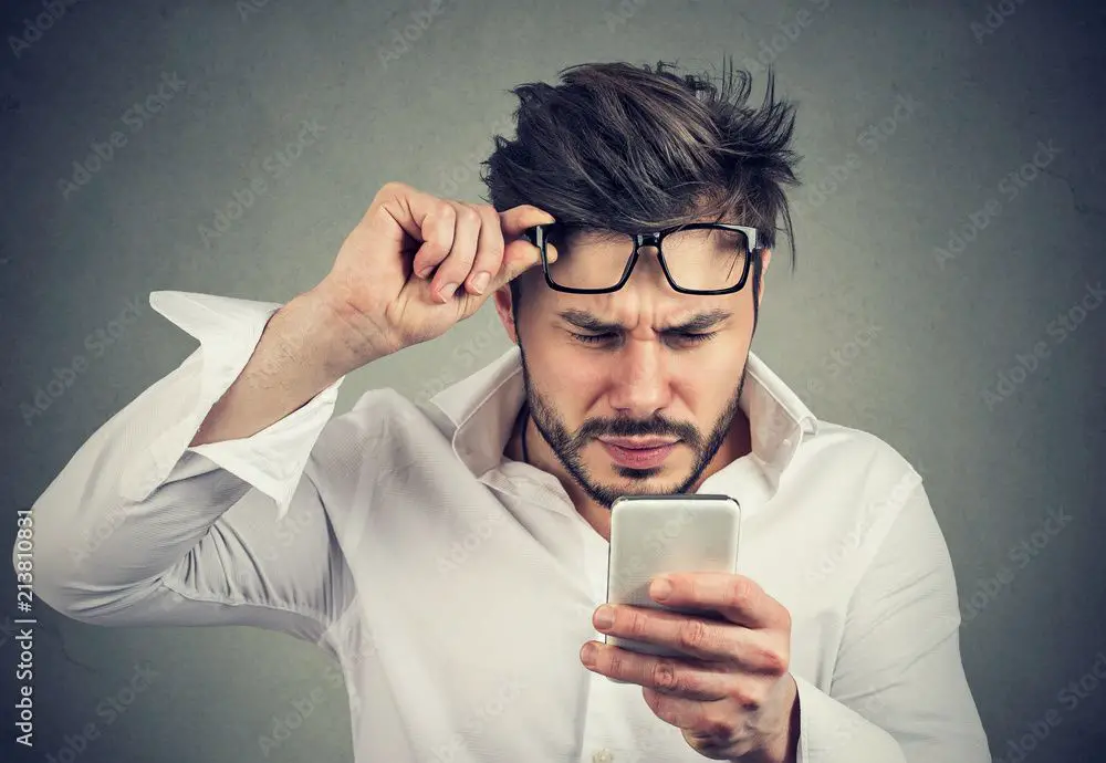 man looking confused as he reads backorder email on his phone