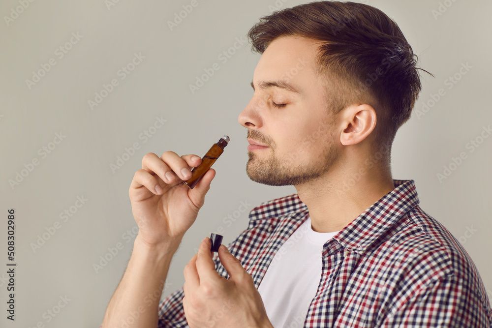man smelling an open bottle of essential oils.