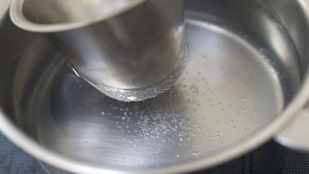 melting candle wax in a stainless steel pot on the stove