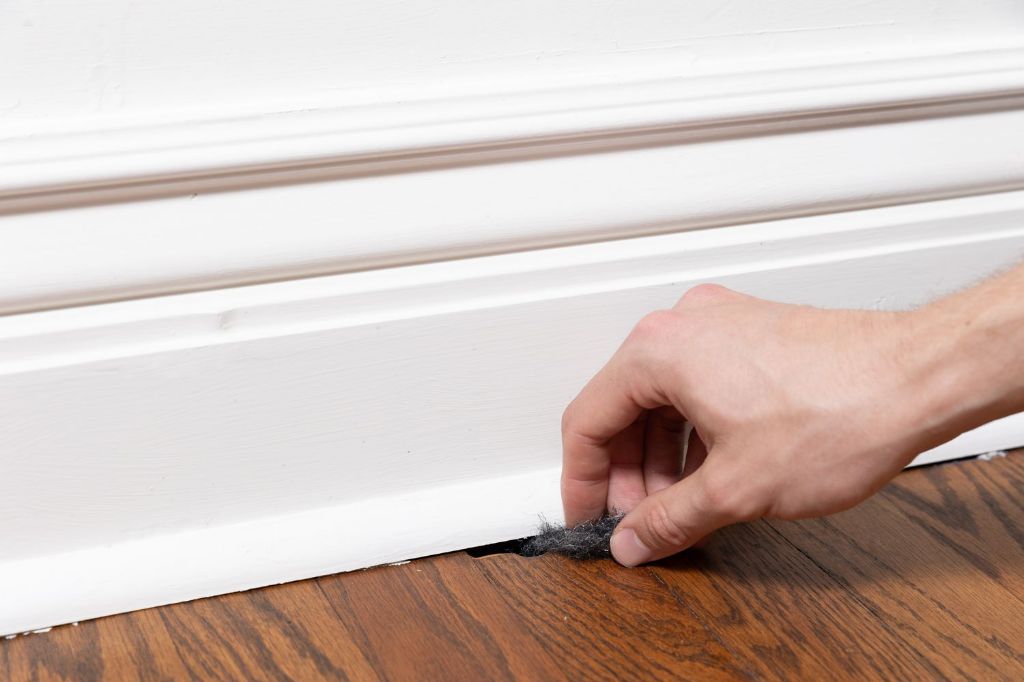 peppermint oil being applied along a baseboard as a natural mouse repellent