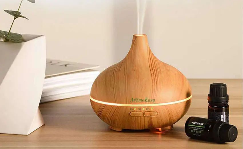 person adding a few drops of essential oil into the water reservoir of an ultrasonic diffuser