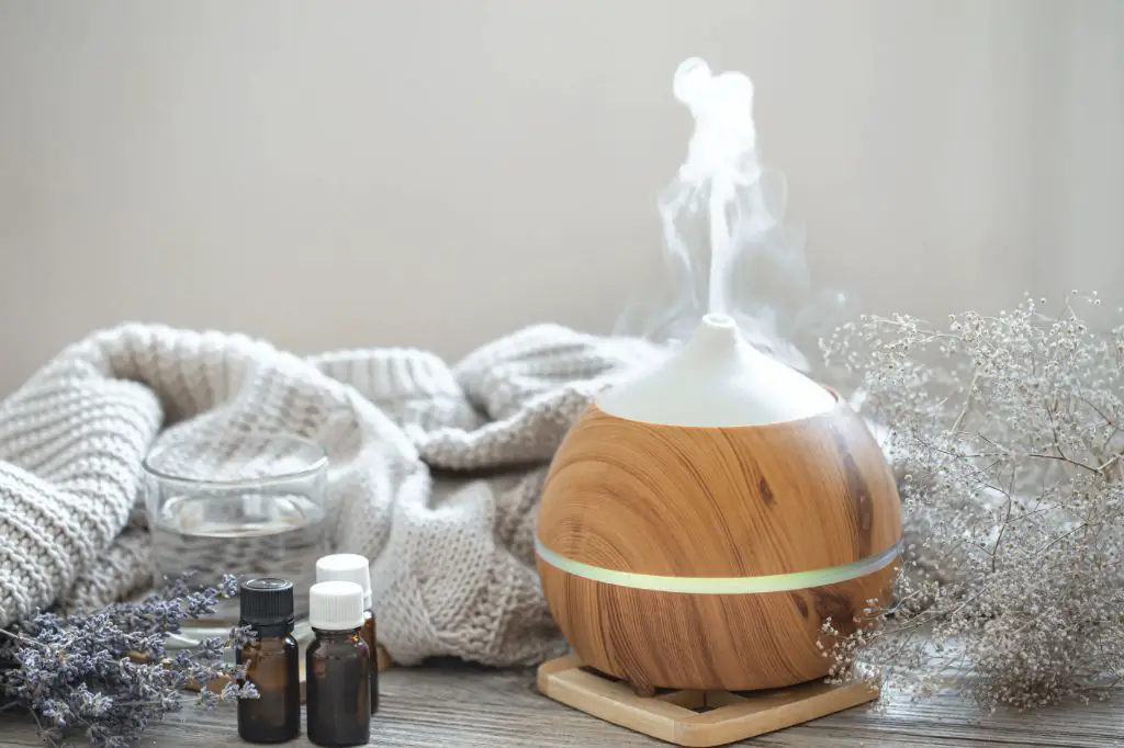 person adding essential oil drops into an ultrasonic diffuser.