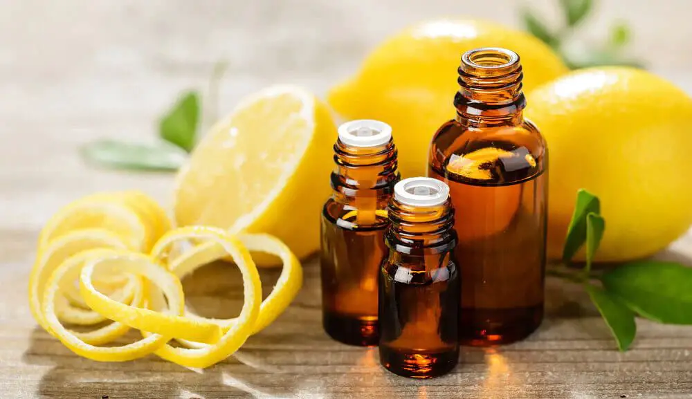 person adding lemon essential oil to a diffuser