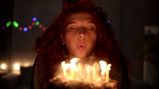 person blowing out a burning candle.