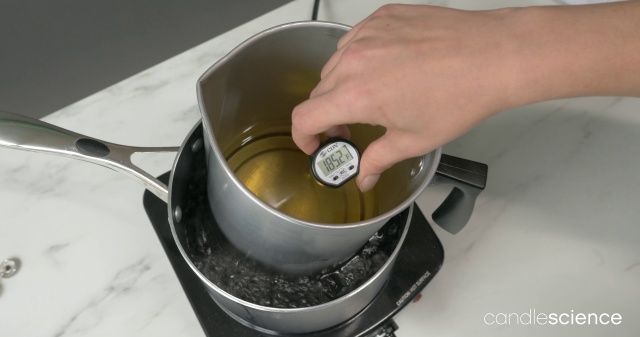 person carefully pouring wax into pot