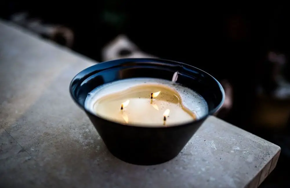 person cutting the wick off a used candle with a knife before melting it down