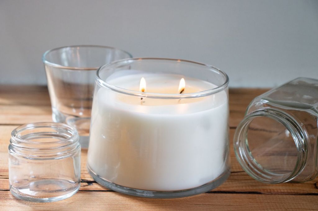 person holding wick bars in a candle container to arrange 3 wicks
