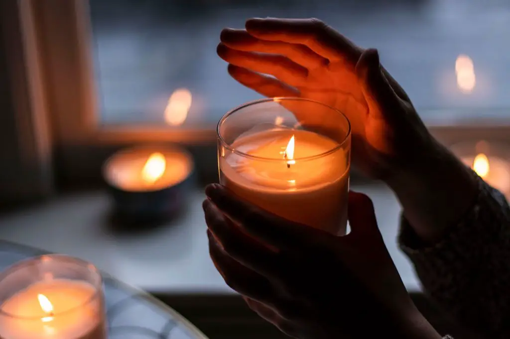 person knocking over tealight candle placed on a rug, spilling melted wax