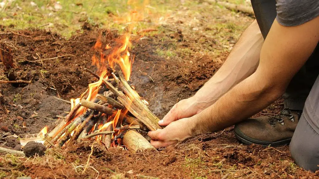 person lighting a fire with natural materials