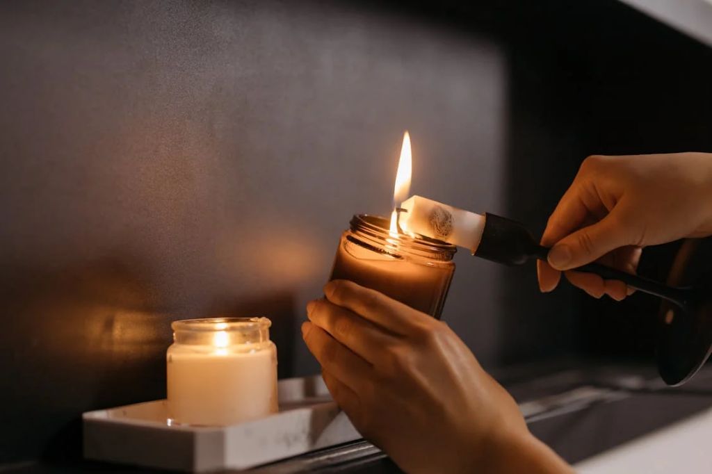 person lighting a tealight candle