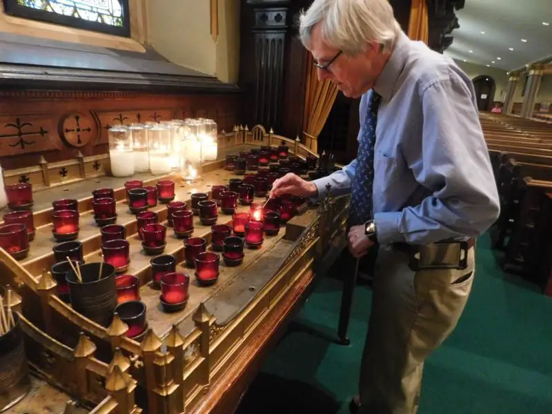 person lighting a votive candle in a church